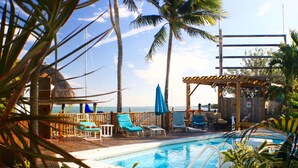 A pool area with lounge chairs, a wooden deck, and a view of the ocean. - Conch Key Fishing Lodge and Marina (Marathon)