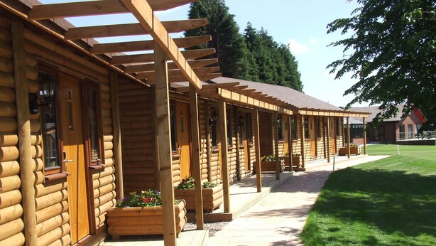 Une rangée de bâtiments de style cabane en rondins, dotés de terrasses en bois et de jardinières.