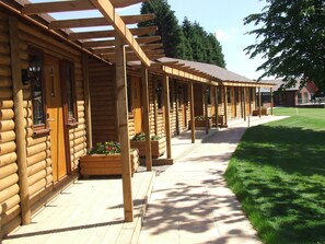 A row of log cabin-style buildings with wooden decks and planters. - Calderfields Golf & Country Club (Walsall)