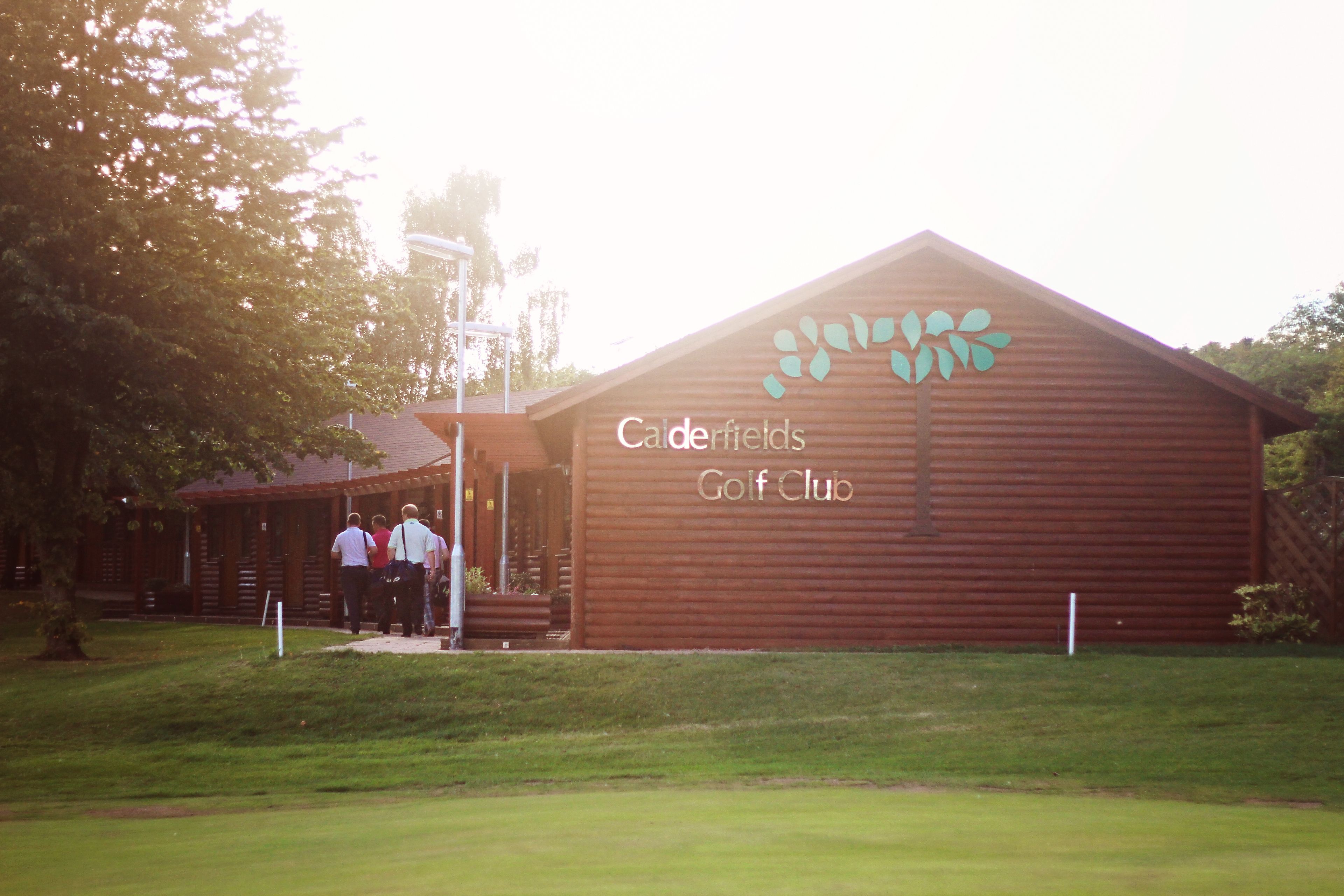 A wooden building with a sign reading "Cedarfields Golf Club".