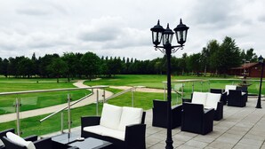 Un espace extérieur aménagé avec des sièges et une vue sur un terrain de golf.