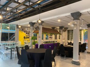 An indoor dining area with round tables, chairs, and columns.