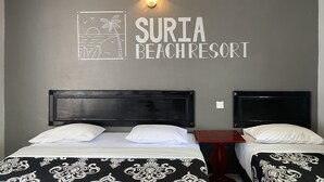 A hotel room with a bed, two bedside tables, a wall-mounted light, and a wall sign reading "SURIA BEACHRESORT". - Suria Beach Resort (Pangkor Island)