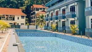 A hotel with a swimming pool, multiple-story buildings, and a tropical garden. - Suria Beach Resort (Pangkor Island)