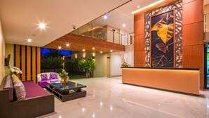 A modern lobby with a reception desk, seating area, and a staircase leading to an upper level. - At The Tree Phuket (Rawai)