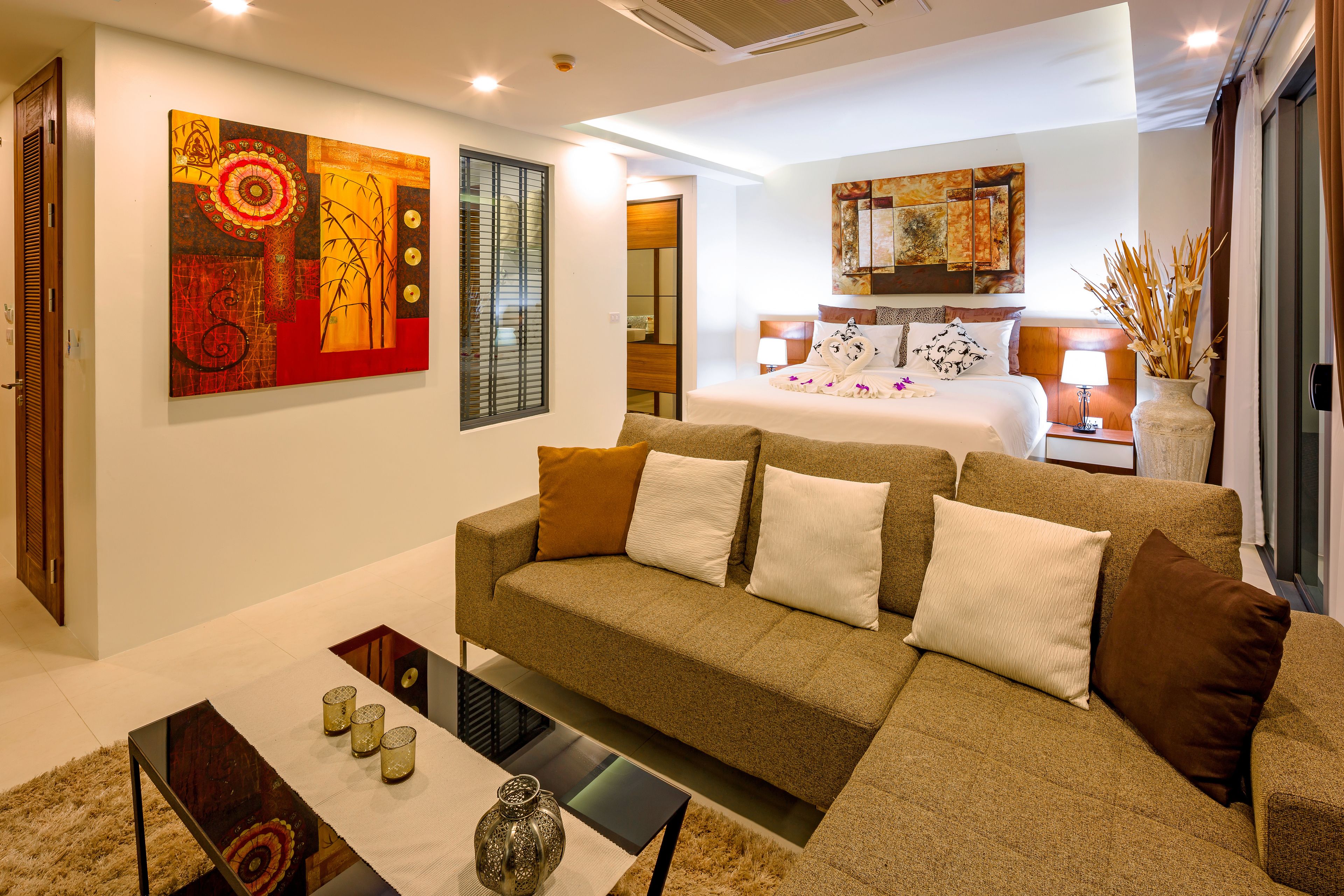 A modern hotel room with a sofa, a small table, and a decorative vase.