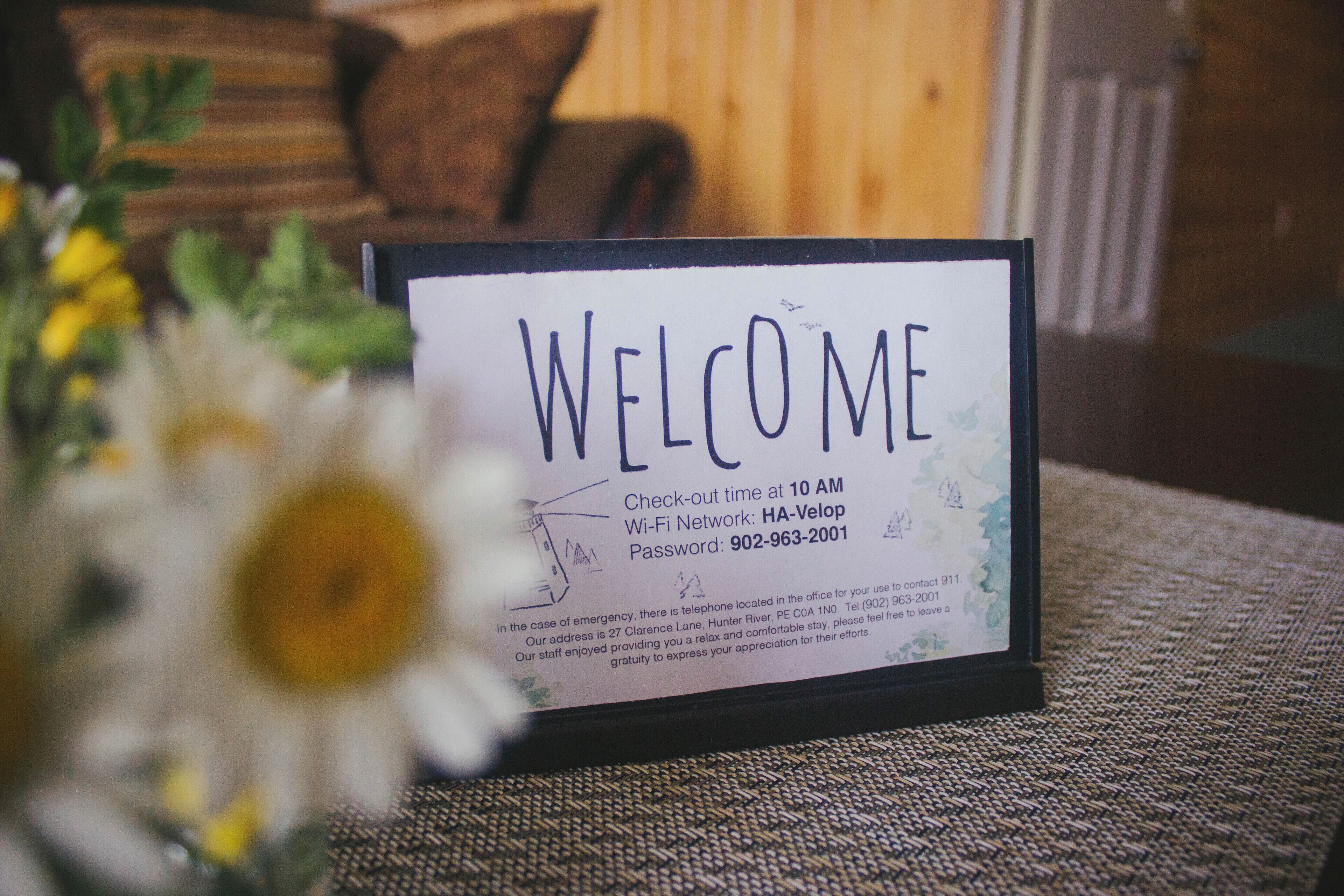 A welcome sign with check-out time, Wi-Fi network, password, and emergency contact information.