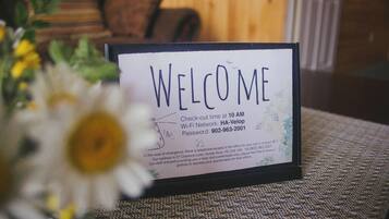 A welcome sign with check-out time, Wi-Fi network, password, and emergency contact information.