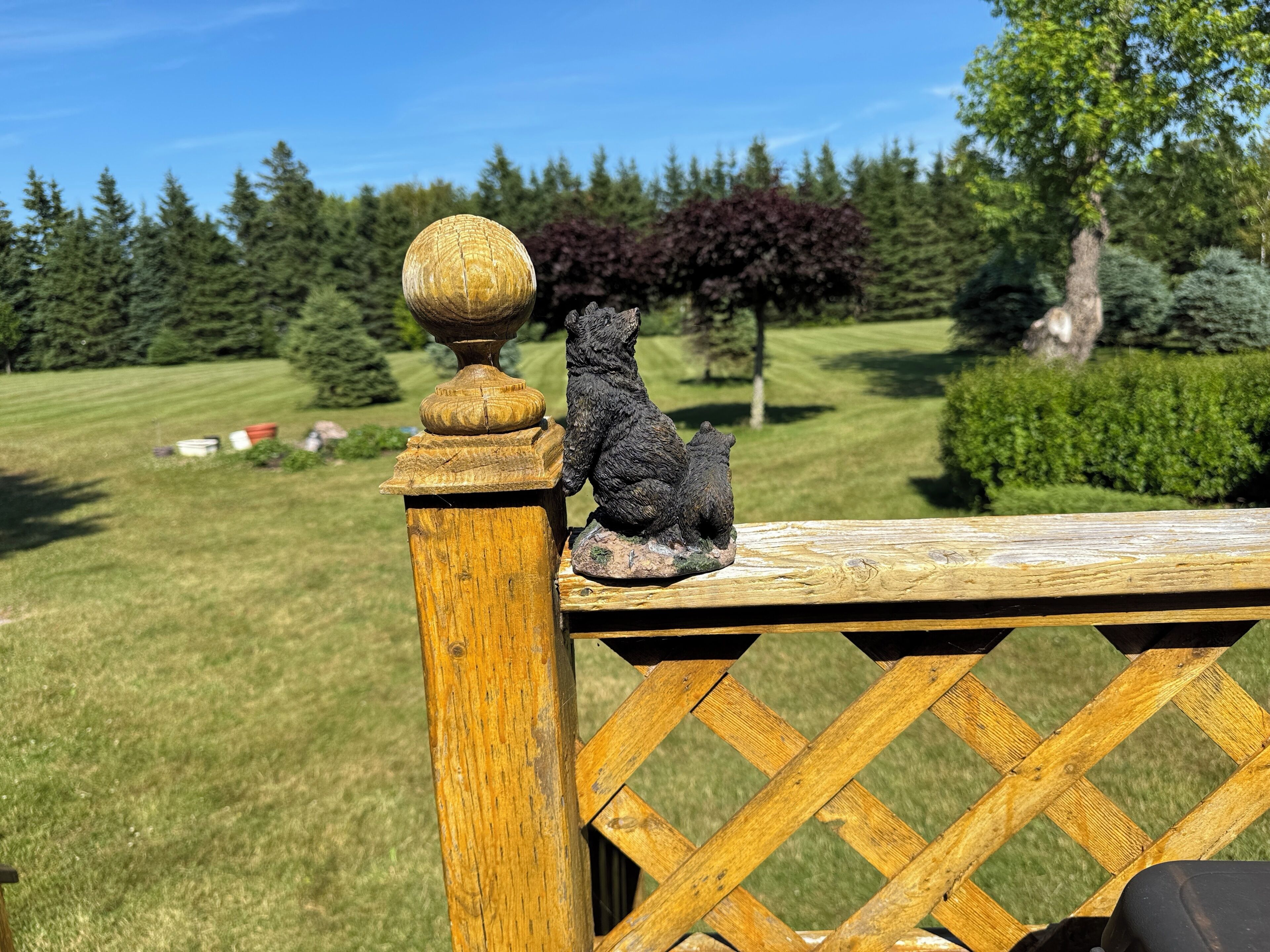 Geländer aus Holz mit einer verzierten Balustrade und einer kleinen Bärenfigur.