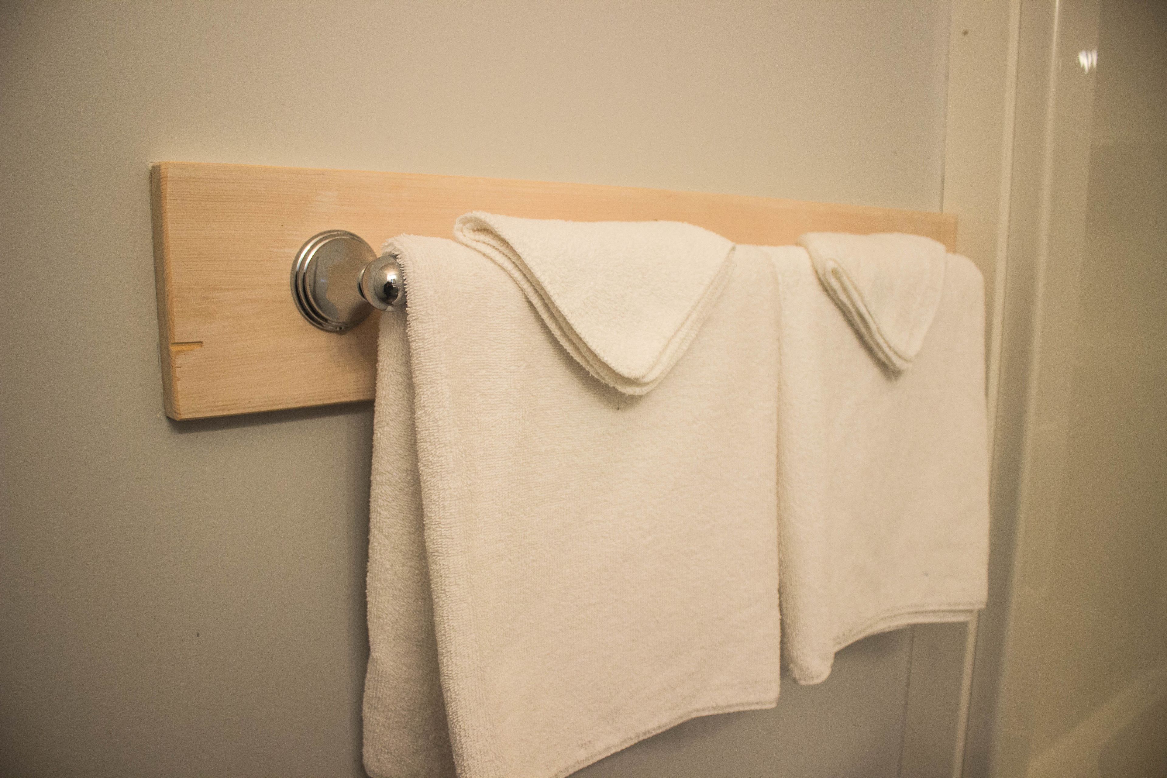 A bathroom with a wooden towel rack holding two white towels.