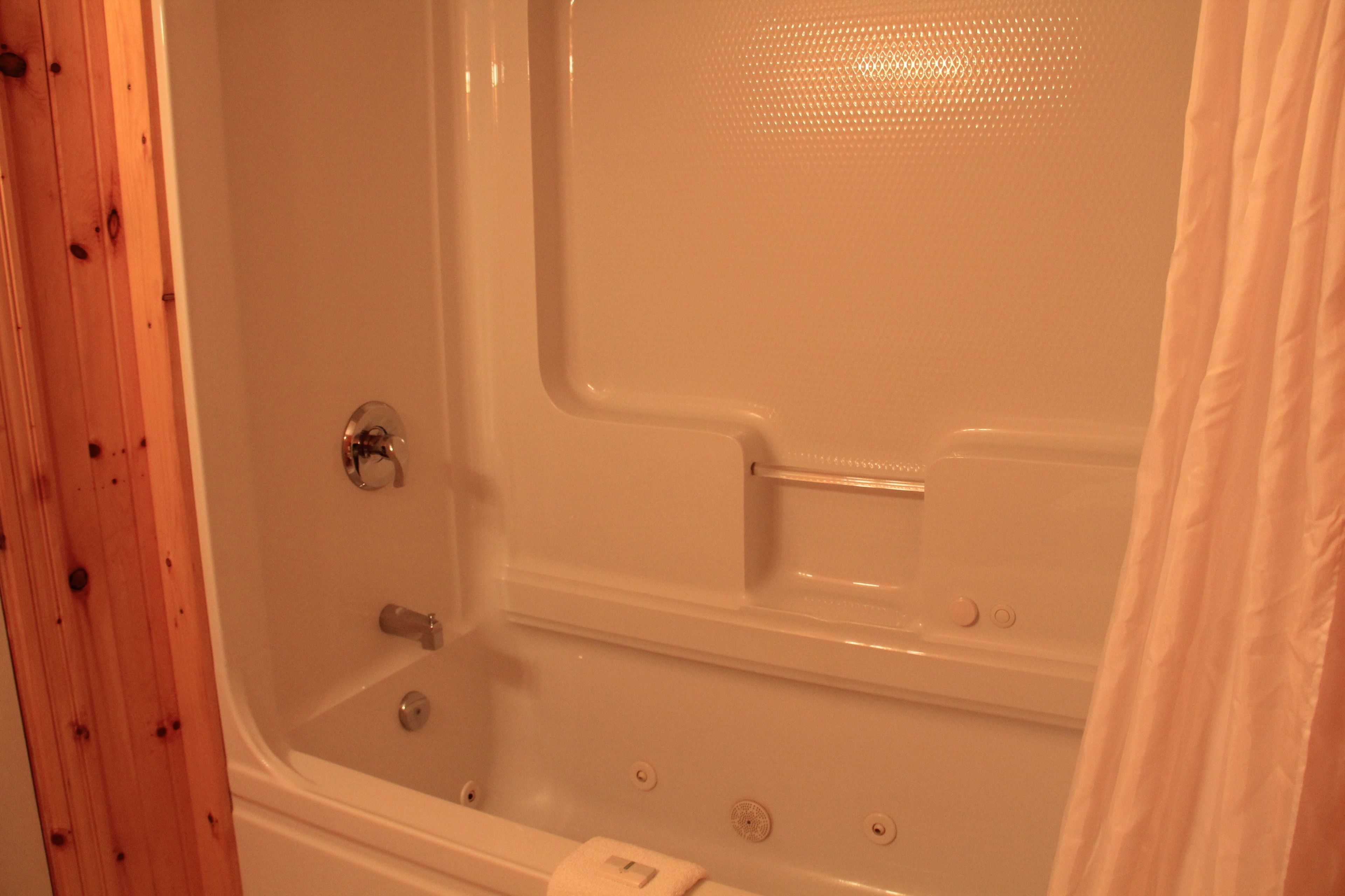 A bathtub with a shower curtain, a towel, and a wooden wall.