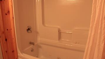 A bathtub with a shower curtain, a towel, and a wooden wall.