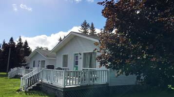 A two-story cabin with a covered porch and a small deck.