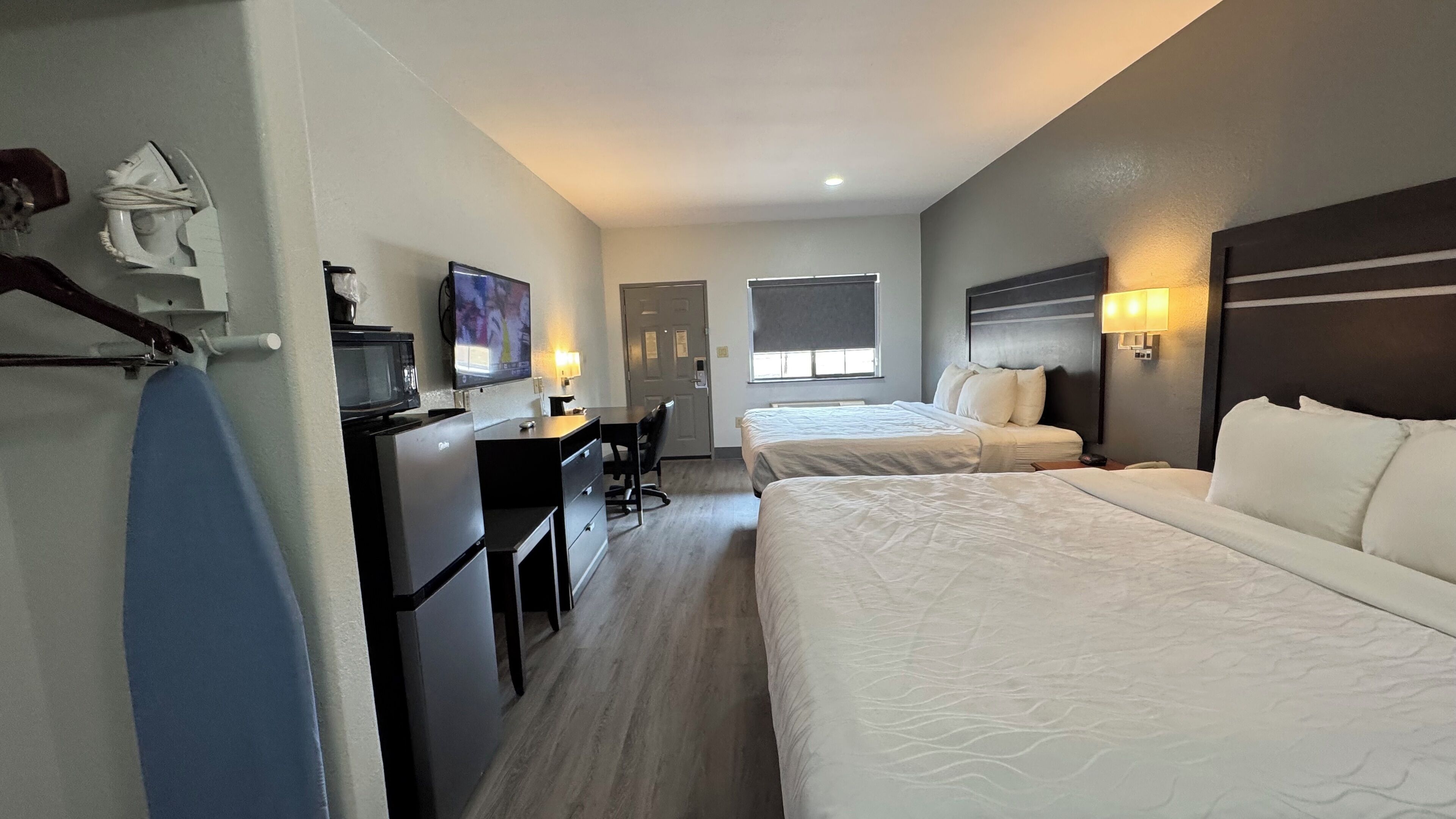 Een hotelkamer met twee bedden, een bureau, een stoel, een magnetron en een televisie.