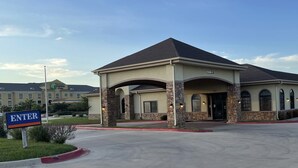 A hotel with a covered entrance, stone pillars, and a sign indicating a handicap accessible entrance. - Sunbridge Inn and Suites (Jourdanton)