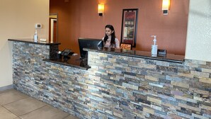 A reception desk with a stone facade, a digital display, and a chair. - Sunbridge Inn and Suites (Jourdanton)