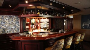 A bar area with a wooden counter, bar stools, and a variety of bottles and glasses. - Restaurant & Hotel Hoog Holten (Holten)