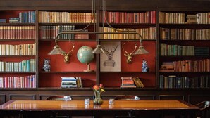 A library with bookshelves, a wooden table, chairs, a globe, and decorative items. - Restaurant & Hotel Hoog Holten (Holten)