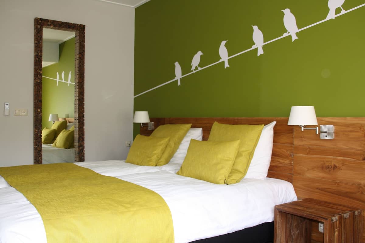 A hotel room with a bed, green wall, and a line of bird silhouettes.