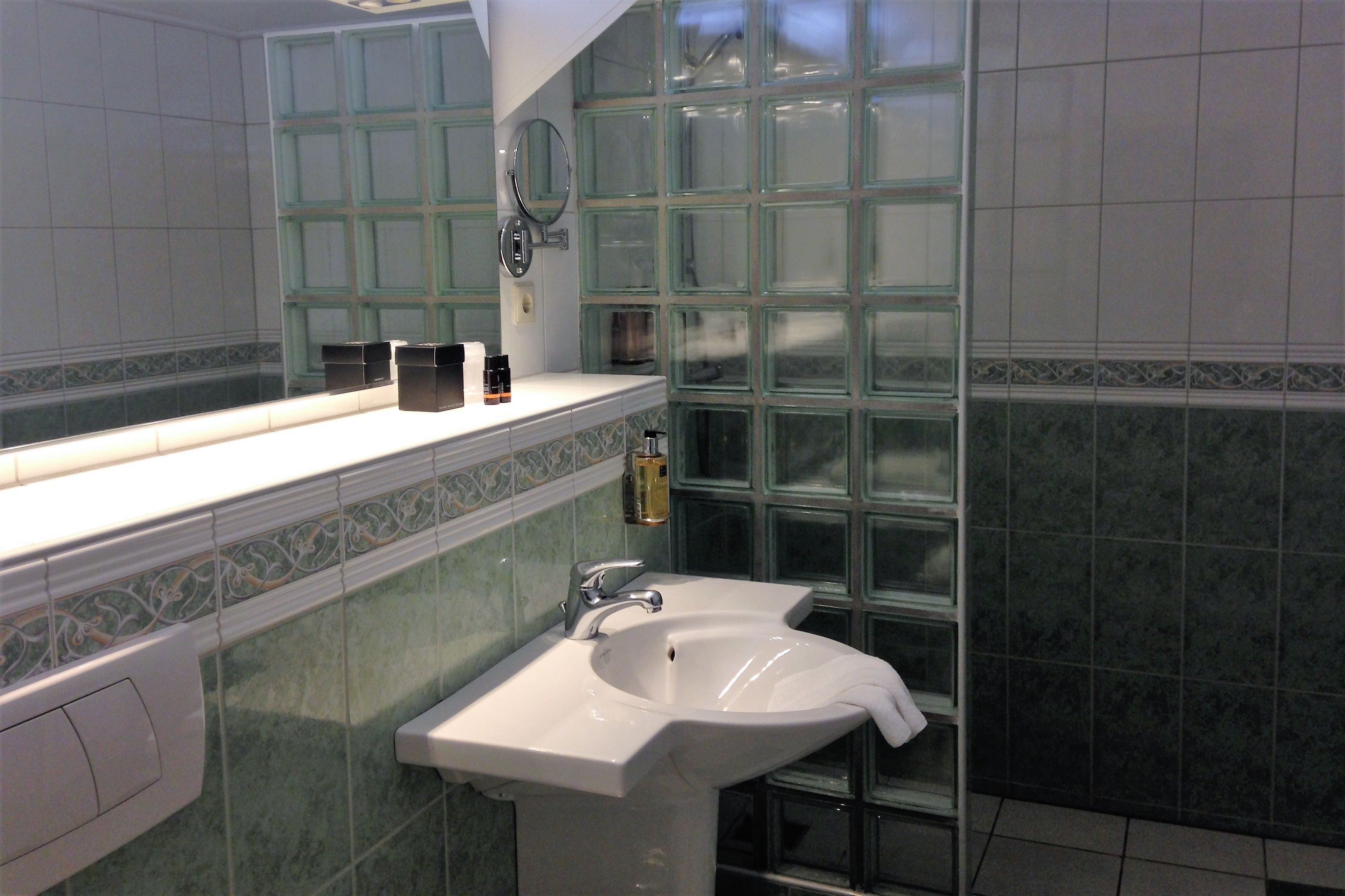 Une salle de bain avec un lavabo, un miroir et un mur en blocs de verre.