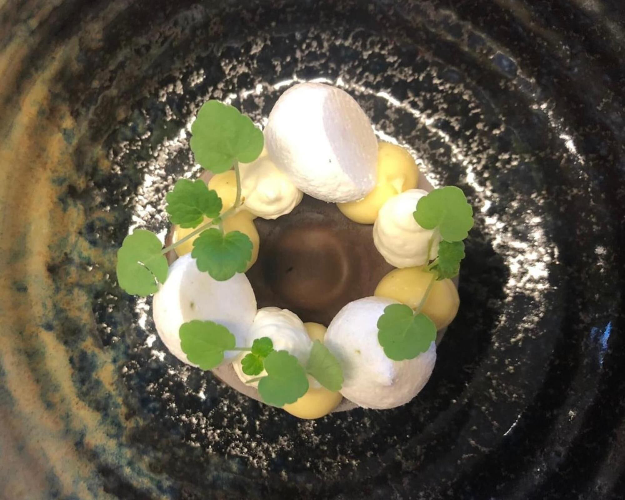 A circular arrangement of white and yellow objects with green leaves in the center, set against a textured background.