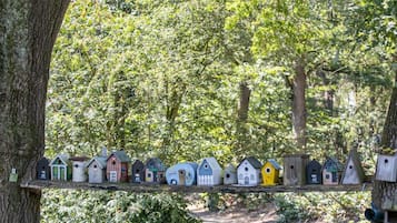 A pathway lined with birdhouses of various shapes and sizes, surrounded by lush greenery and trees.