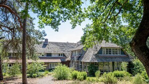 A house with a thatched roof, surrounded by trees and a gravel driveway. - Restaurant & Hotel Hoog Holten (Holten)