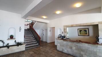 A spacious lobby with a staircase, a reception desk, and a fireplace.