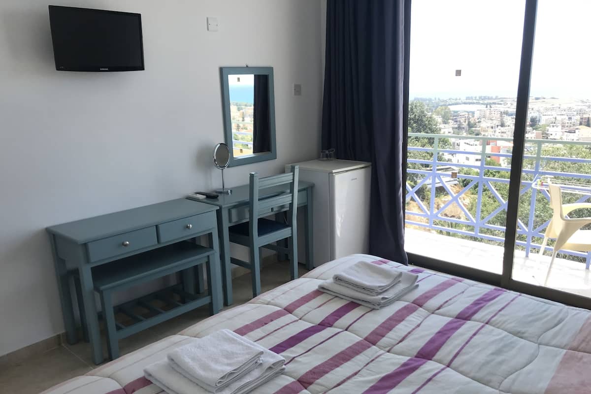 Une chambre d’hôtel avec un lit, un bureau, une chaise, un miroir et une télévision.
