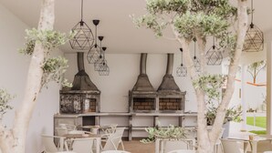 A restaurant with a rustic interior, featuring exposed brick walls, a long counter, and multiple hanging light fixtures. - Neptuno (Peniche)