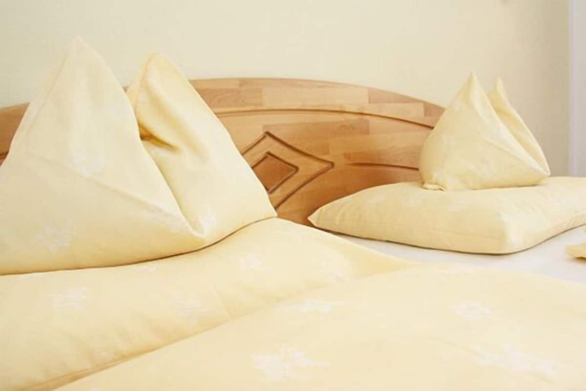 A bed with a wooden headboard and two pillows.