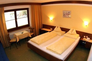 A hotel room with two beds, a desk, a chair, and a small table. - Stefanihof Hotel (Fuschl am See)