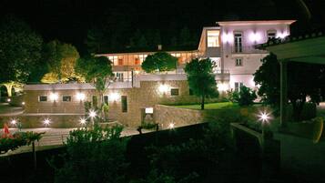 A multi-story building with a stone facade, multiple windows, and a well-lit entrance area.