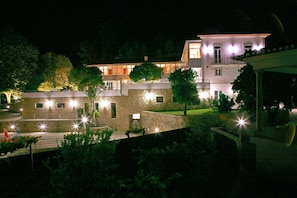 A multi-story building with a stone facade, multiple windows, and a well-lit entrance area. - Hotel Quinta Progresso (Vale de Cambra)