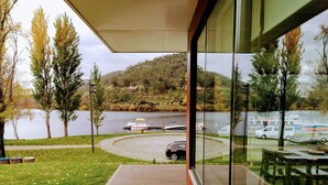 A view from a balcony overlooking a lake with boats, a car, and a grassy area with trees. - VilaPortuguesa (Vila Velha de Rodao)
