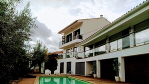 A modern two-story house with a swimming pool, wooden deck, and potted plants. - VilaPortuguesa (Vila Velha de Rodao)