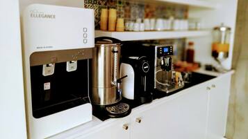 En kaffemaskin och en vattenkokare står på en köksbänk.