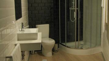 A modern bathroom with a glass-enclosed shower, a white sink, and a toilet.