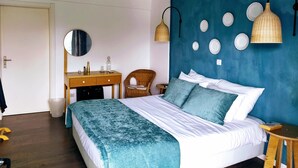 A bedroom with a bed, a dresser, a chair, a wall-mounted mirror, and a wall with circular plates. - VilaPortuguesa (Vila Velha de Rodao)