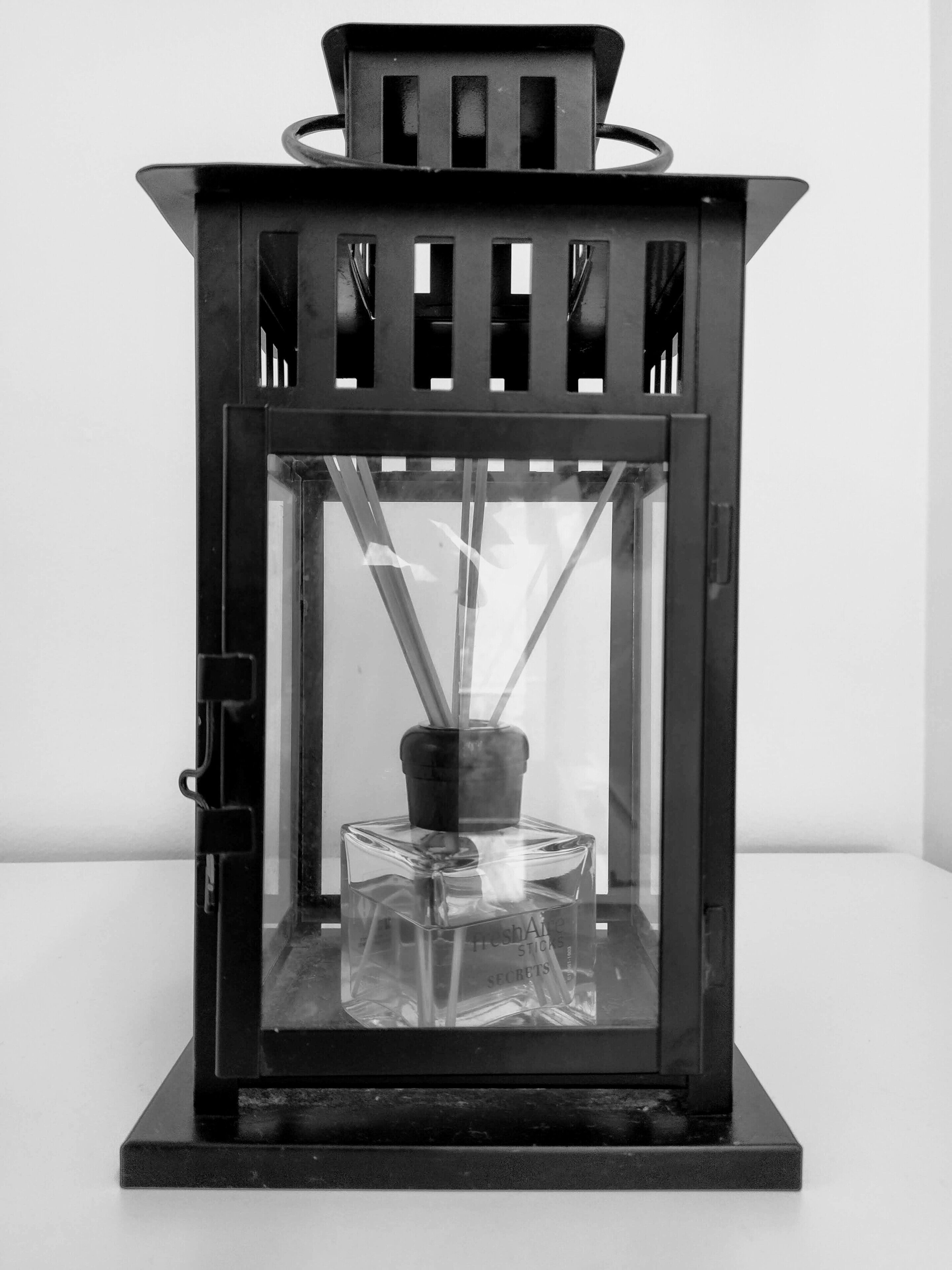 A black lantern with a glass enclosure and a candle holder inside.