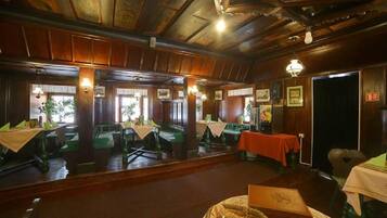 Un restaurante con paneles de madera y asientos tipo cabina en color verde. Las mesas están dispuestas con manteles blancos y servilletas verdes.