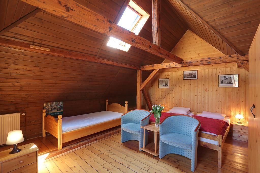 A cozy wooden cabin room with two beds, a table, and a chair.