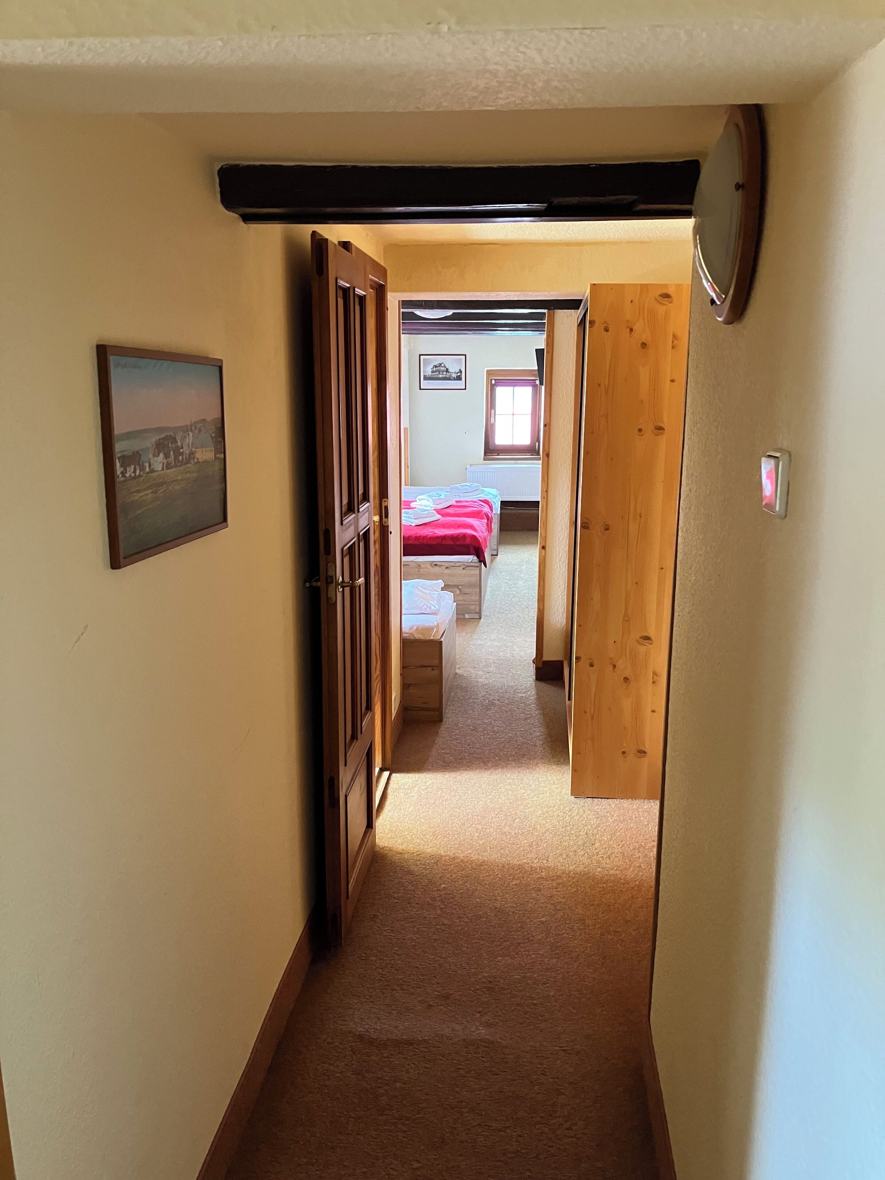 Un pasillo estrecho que conduce a un dormitorio con cama y ventana.