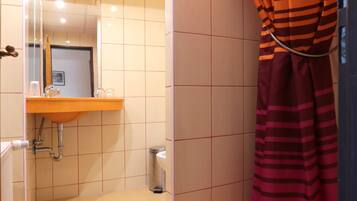 A bathroom with a shower, a sink, and a mirror.