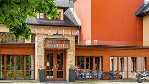 A hotel entrance with a stone facade, large windows, and outdoor seating. - Golf hotel Morris (Marianske Lazne)