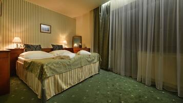 A hotel room with a bed, two bedside tables with lamps, a mirror, and a window with curtains.