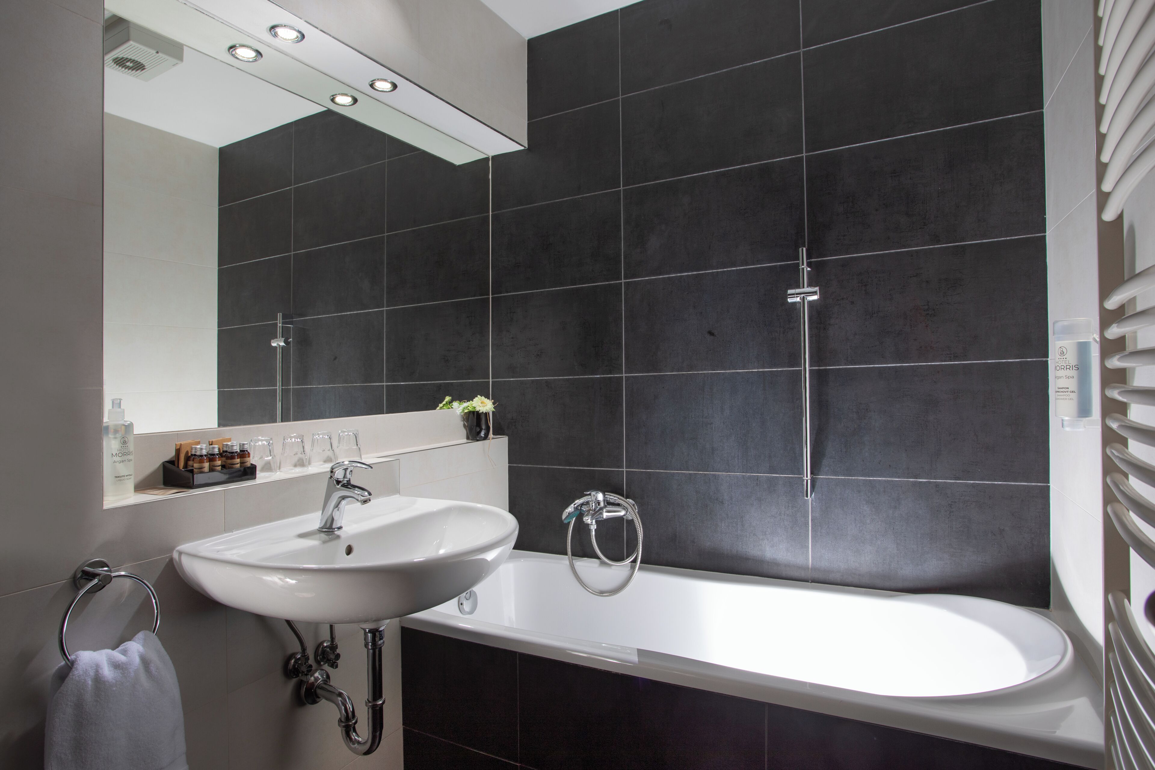 A modern bathroom with a large bathtub, a sink, and a mirror.