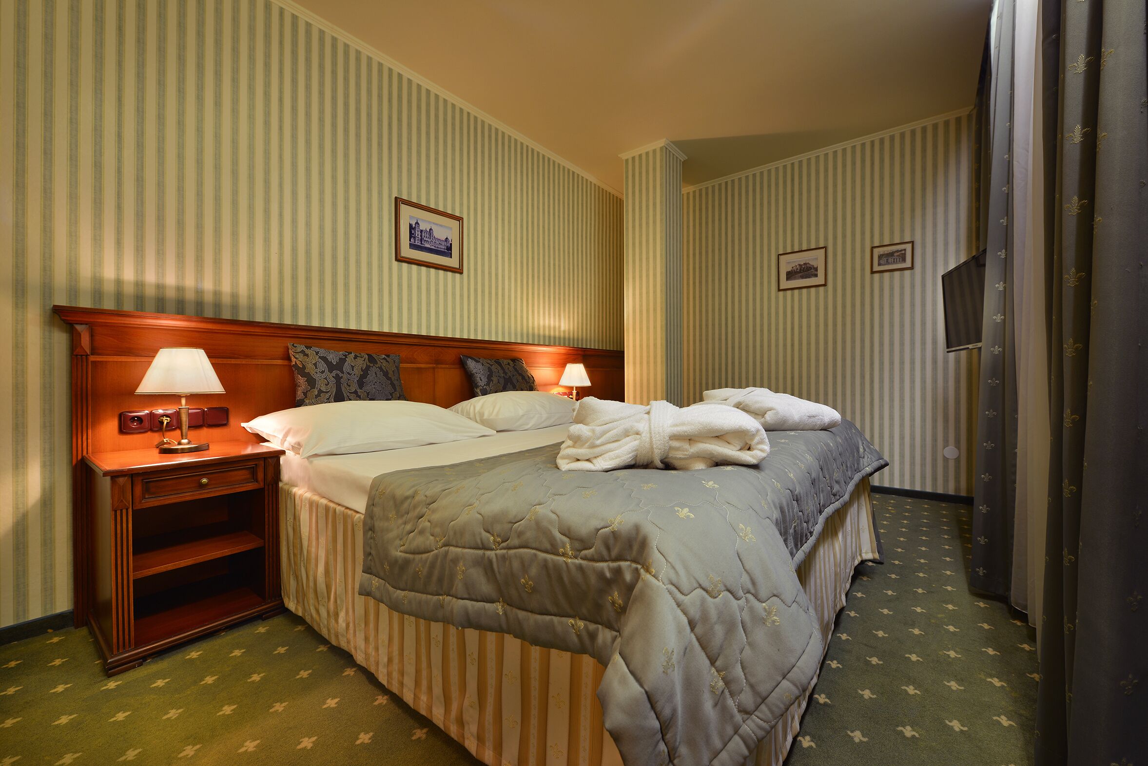 Una habitación de hotel con una cama, una mesita de noche, una lámpara y un cuadro en la pared.