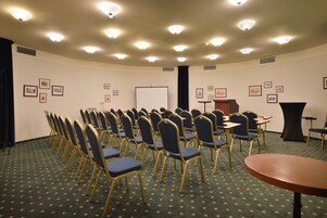 Un salón de conferencias con filas de sillas, un atril y una pizarra.