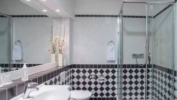 Un baño moderno con cabina de ducha de vidrio, un lavabo blanco y un inodoro.